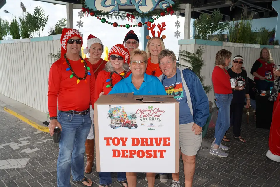 Volunteers in Santa hats holding the Toy Drive Deposit box at Caddy's