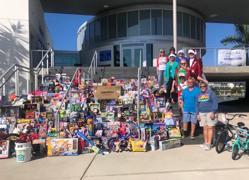 Volunteers on the Madeira Beach Commission Chambers steps behind hundreds of donated toys and new kids' bikes